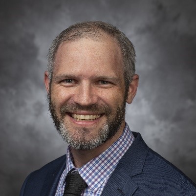 A person with a beard smilingDescription automatically generated with low confidence